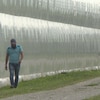 Un homme marche à côté d'un grand mur transparent qui semble être en plastique. 