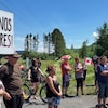 Un homme tient une pancarte «Ouvrez nos frontières!», entouré d'une dizaine de personnes, dont certaines tiennent des drapeaux du Canada. 