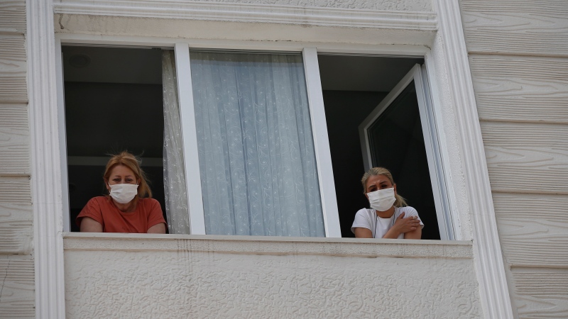 In this May 15, 2020 photo, a woman who had been experiencing COVID-19 symptoms looks from her window in Istanbul. (AP Photo/Emrah Gurel)