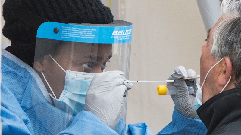 A health-care worker prepares to swab a man at a walk-in COVID-19 test clinic in Montreal North, Sunday, May 10, 2020, as the COVID-19 pandemic continues in Canada and around the world. THE CANADIAN PRESS/Graham Hughes
