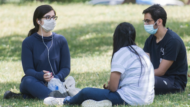 People wear face masks as they gather in a city park on Canada Day in Montreal, Wednesday, July 1 2020, as the COVID-19 pandemic continues in Canada and around the world. THE CANADIAN PRESS/Graham Hughes