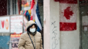 A pedestrian wears a protective mask as she walks in the winter weather downtown in Toronto on Wednesday, February 26, 2020. THE CANADIAN PRESS/Nathan Denette