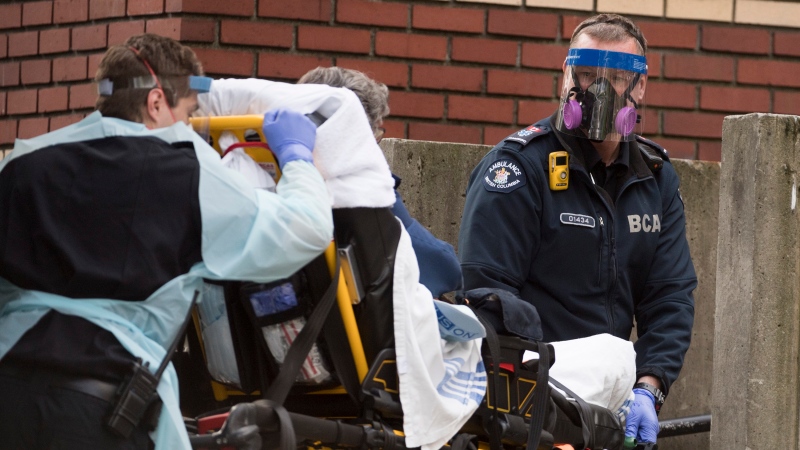 Members of the B.C. Ambulance Service wear protective face masks and shields as they transfer a patient to St. Paul's hospital in Vancouver, Monday, May 4, 2020. THE CANADIAN PRESS/Jonathan Hayward