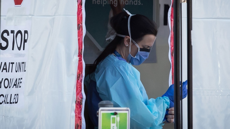 A hospital worker puts on gloves at a COVID-19 assessment centre for staff at Lions Gate Hospital, in North Vancouver, on Thursday, March 19, 2020. THE CANADIAN PRESS/Darryl Dyck