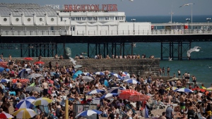 In this file photo dated Wednesday, June 24, 2020, large numbers of people relax on the beach in Brighton, England. (AP Photo/Matt Dunham, File)