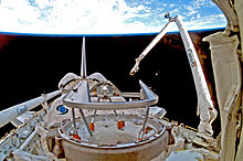 A shuttle in space, with Earth in the background. A mechanical arm labelled "Canada" rises from the shuttle.