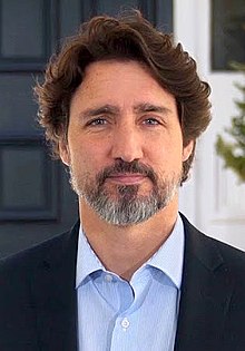 Portrait photograph of Trudeau smiling in front of Rideau Cottage.