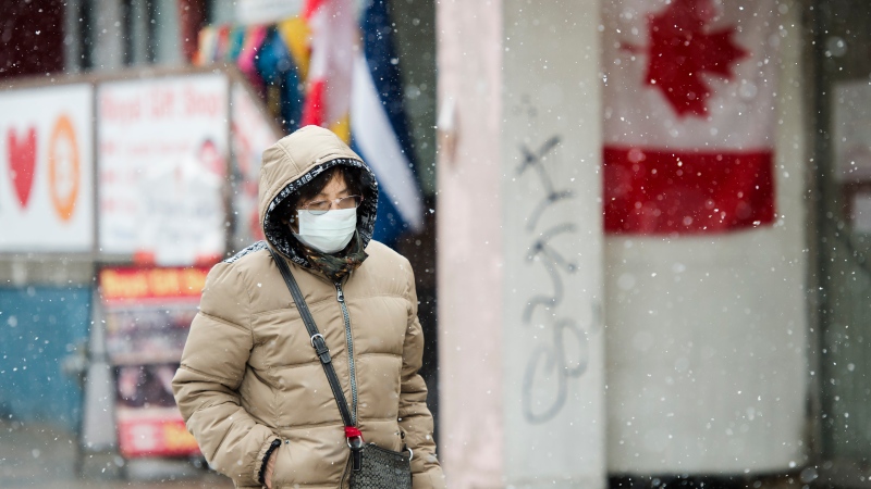 A pedestrian wears a protective mask as she walks in the winter weather downtown in Toronto on Wednesday, February 26, 2020. THE CANADIAN PRESS/Nathan Denette