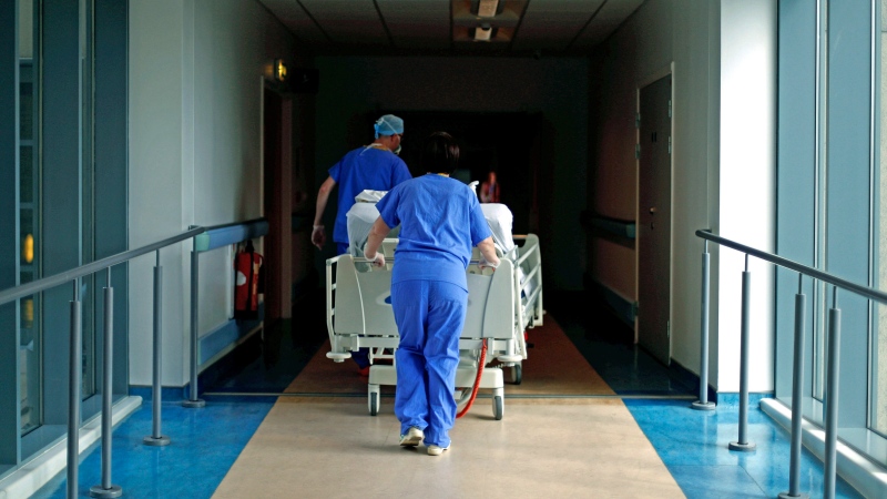 In this Thursday, May 14, 2020 photo, medical staff transfer a patient through a corridor at the Royal Blackburn Teaching Hospital, in Blackburn, England, amid the coronavirus pandemic. (Hannah McKay/Pool Photo via AP)