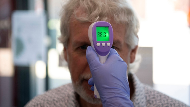 In this Tuesday, June 9, 2020 photo, a patient has his temperature taken with a non-contact infrared thermometer in Grimsby, northeast England. (Daniel Leal-Olivas/Pool Photo via AP)