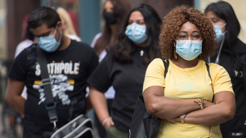 People wear face masks as they wait to enter a store in Montreal, Saturday, Sept. 5, 2020, as the COVID-19 pandemic continues in Canada and around the world. THE CANADIAN PRESS/Graham Hughes