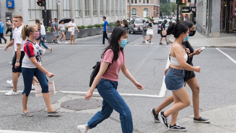 People wear face masks as they cross a street in Montreal, Sunday, August 9, 2020, as the COVID-19 pandemic continues in Canada and around the world. THE CANADIAN PRESS/Graham Hughes
