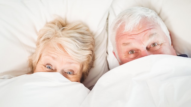Un couple se cache sous les couvertures.