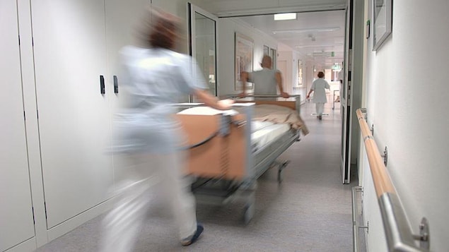 Des infirmières poussent un lit dans un couloir d'un hôpital.