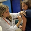Une infirmière vaccine une jeune fille dans le bras. 