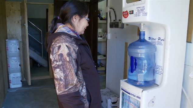 Une femme autochtone remplit un bidon d’eau à une station de remplissage