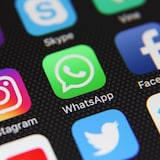 Une photo d'un écran de téléphone intelligent sur lequel sont affichés les icônes de différents réseaux sociaux. Ceux d'Instagram, de WhatsApp et de Facebook sont mis en évidence au centre.