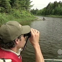 Un homme qui regarde avec des jumelles sur un lac.