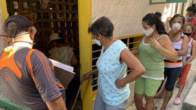 People queue at a soup kitchen in Catia
