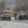 Une voiture de police stationnée devant un autobus scolaire qui a fait une sortie de route.