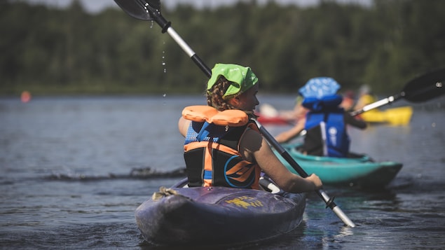 Des enfants font du kayak sur un lac.