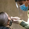 Un homme fait un prélèvement sur une femme dans le cadre d'un test de dépistage de la COVID-19.