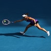 Une joueuse de tennis s'étire pour frapper une balle lors d'un match disputé sur un terrain bleu. 