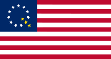A modified version of the American flag with ten white stars and three gold stars forming a letter Q.
