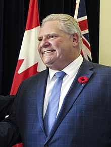 Ford in 2018 wearing a navy blue suit and a poppy.