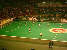 Photo des gradins d'une salle de sport où se joue une partie de futsal.