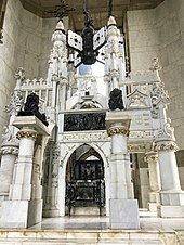 A large white, black, and gold tomb elaborately adorned with sculpture and writing, claiming to be the resting place of Cristobal Colon.