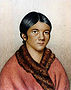 "A bust color portrait of a young Aboriginal woman, in a red traditional shawl with her dark hair tied back "