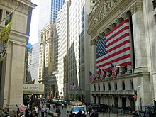 A large flag is stretched over Roman style columns on the façade of the New York Stock Exchange