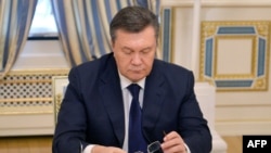 Viktor Yanukovych looks down at his glasses before signing an agreement in Kiev on February 21 to end the country's worst crisis since independence.