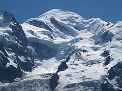 Panorama of Mont Blanc mountain range above grey clouds under a blue sky