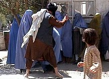 A Taliban religious policeman beating a woman because she removed her burqa in public.