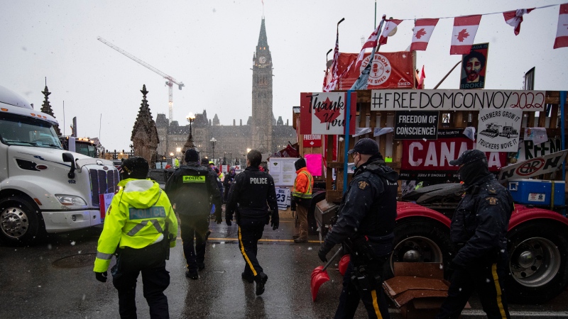 Police walk through parked trucks to make an arrest on Wellington Street, on the 21st day of a protest against COVID-19 measures that has grown into a broader anti-government protest, in Ottawa, on Thursday, Feb. 17, 2022. THE CANADIAN PRESS/Justin Tang