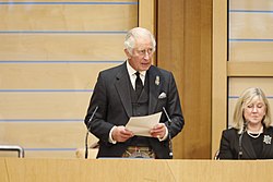 Charles giving a speech to the Scottish Parliament after his mother's death, with the Presiding Officer of the Scottish Parliament Alison Johnstone seated next to him