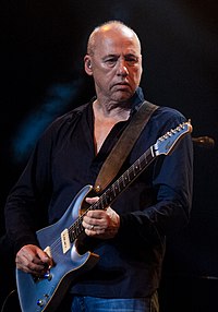 Musician Mark Knopfler playing an electric guitar.