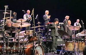 King Crimson at the Sapporo Culture Arts Theatre in Japan, on 2 December 2018. From left to right: Pat Mastelotto, Tony Levin, Bill Rieflin, Jeremy Stacey, Jakko Jakszyk, Gavin Harrison and Robert Fripp (Mel Collins not shown)