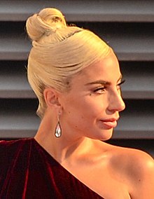 Lady Gaga with her hair in a bun atop her head, looks to the left.