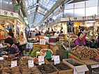 Vendors sell root vegetables at Gyeongdong Market, a crowded indoor mall with a glass roof