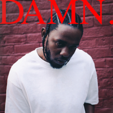 Kendrick Lamar dressed in a white shirt behind red bricks. The word "DAMN." appears on the top in red.