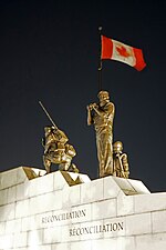 a statue of a person in front of a flag and two other persons kneeling down